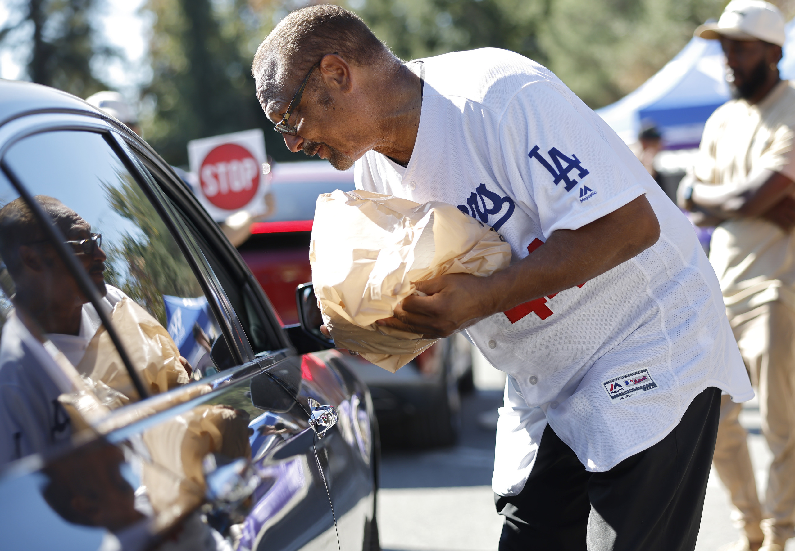 Former Los Angeles Dodger Ken Landreaux delivers a free turkey at a large-scale drive-through turkey meal offering amid the federal government shutdown.