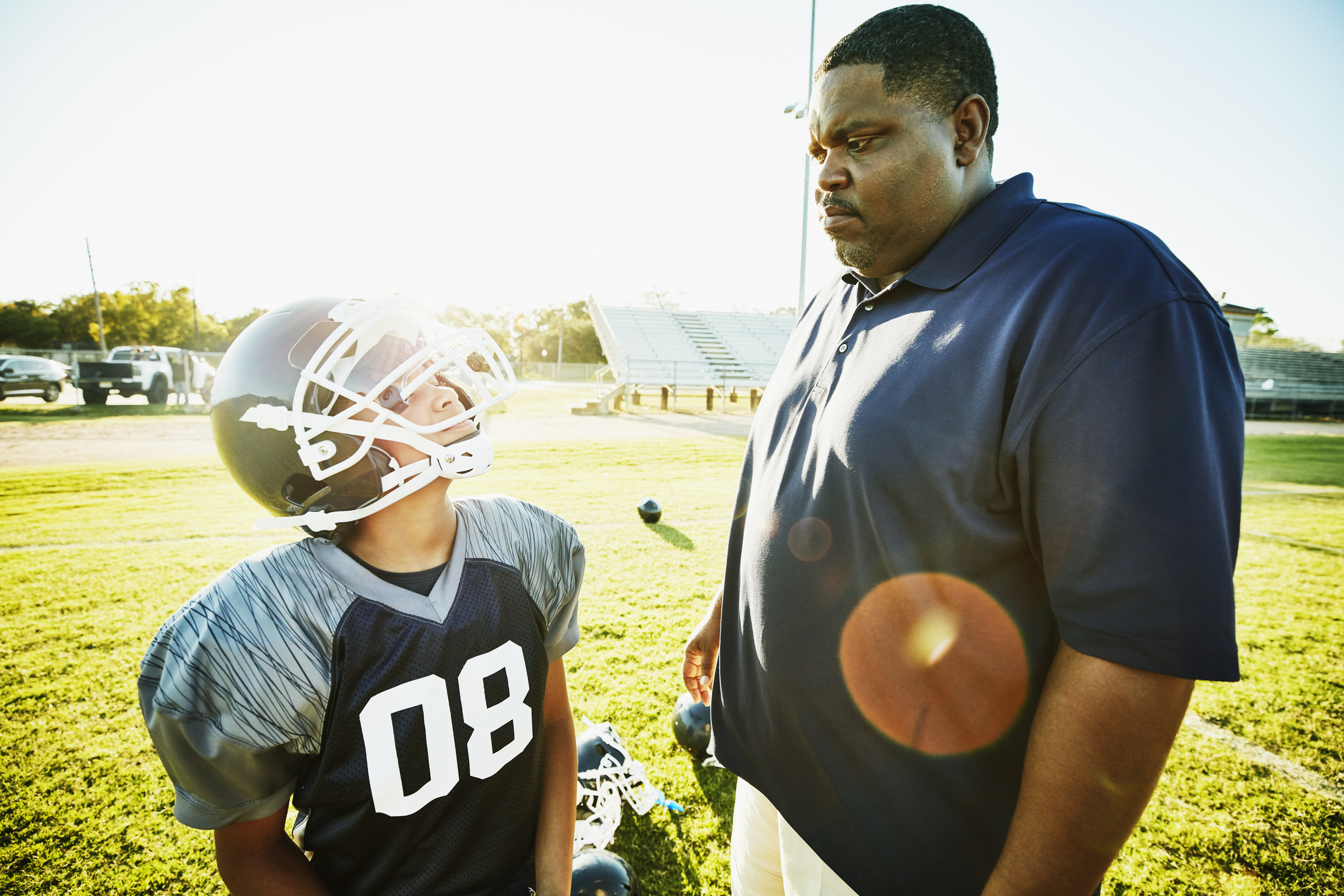 Young football player looking up to coach after football practice
