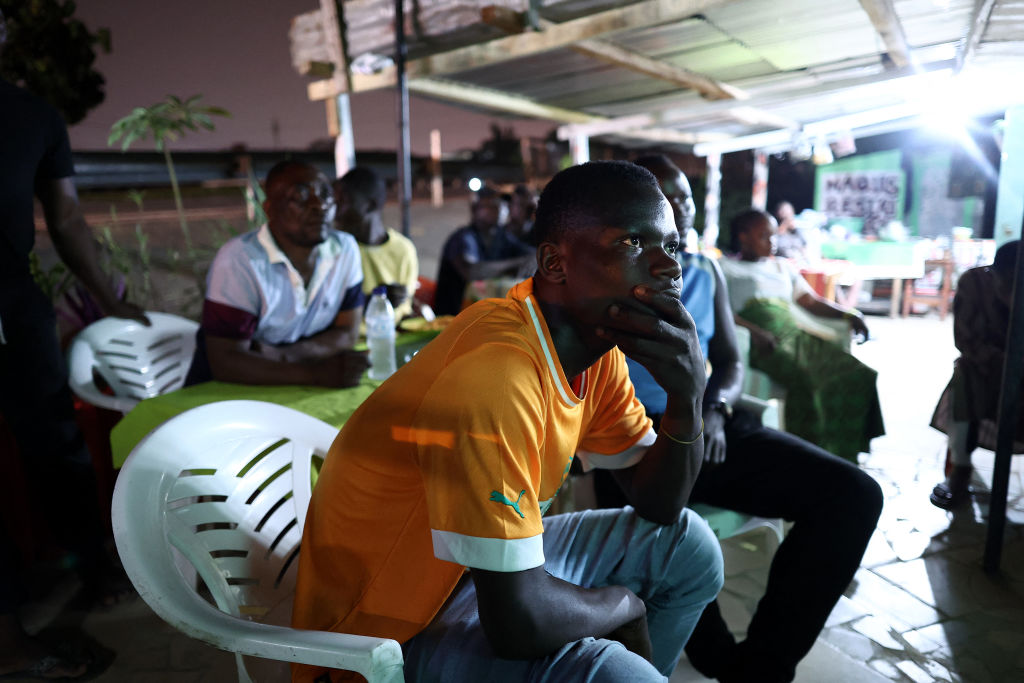 An Ivory Coast's supporter gestures as he watches on a TV.